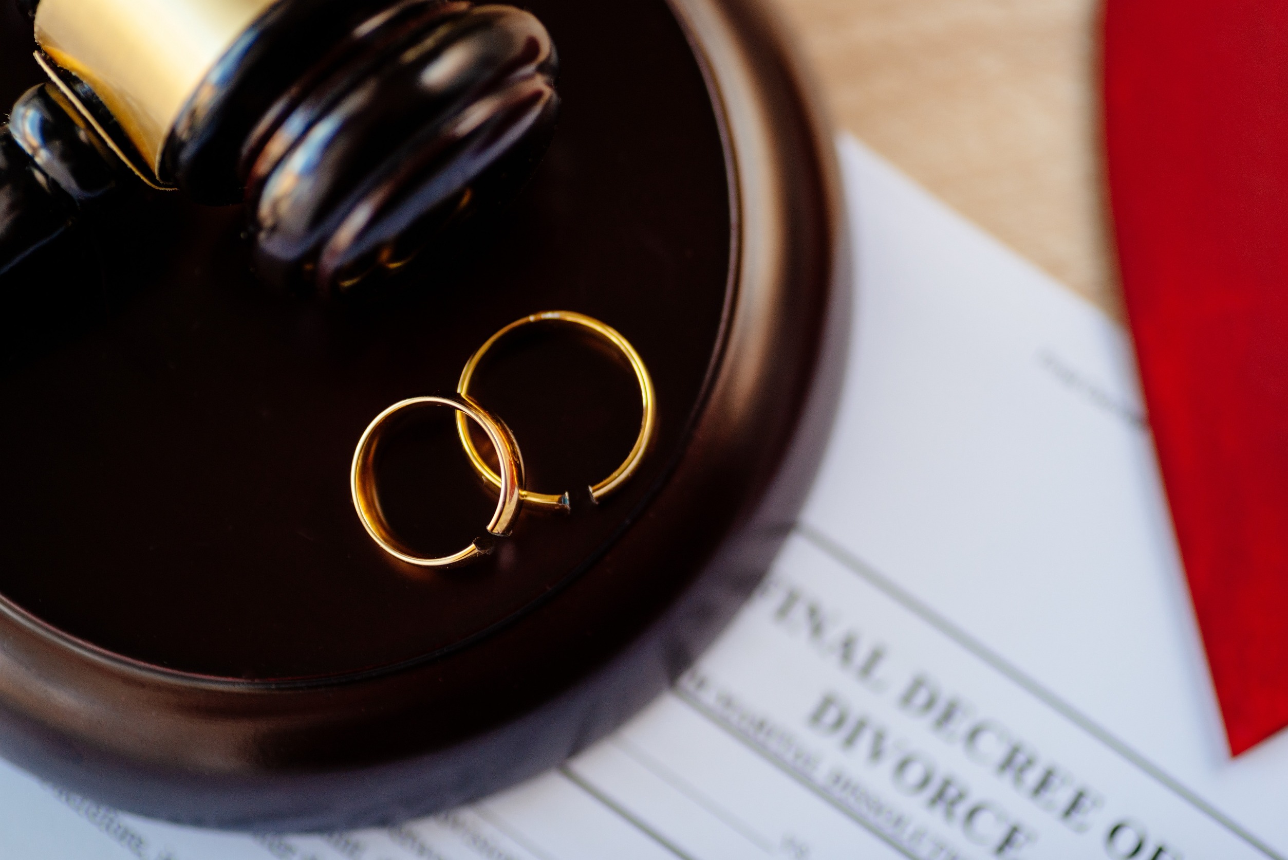 Two broken golden wedding rings on the judge's gavel, signifying divorce and separation.