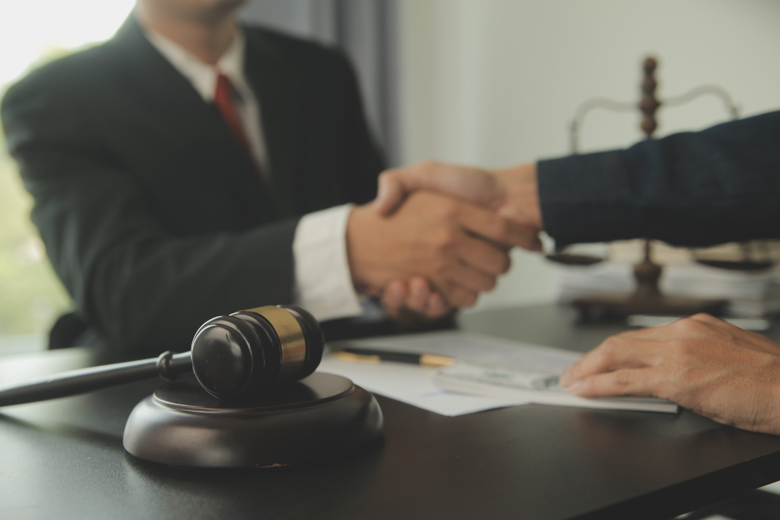 The lawyer and the client shake hands with gravel placed on the table.